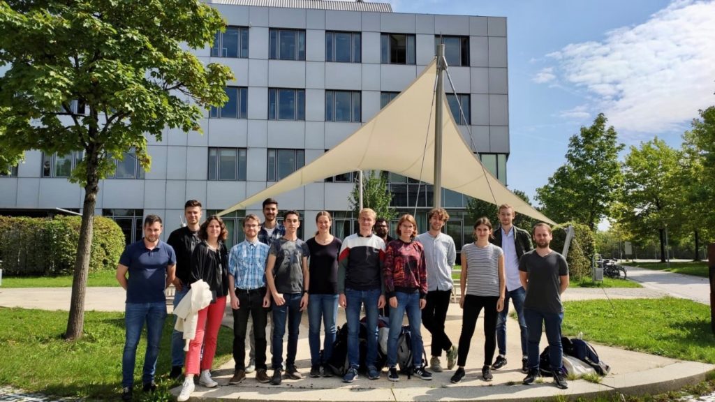 A group of people posing for a photo in front of a building
Description automatically generated