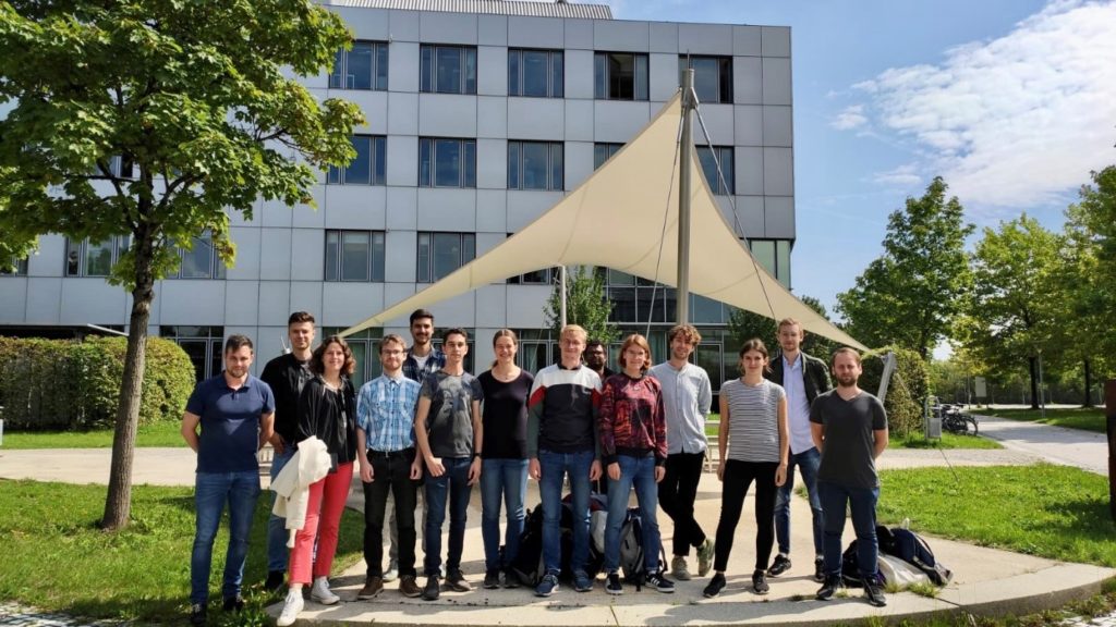 A group of people posing for a photo in front of a building

Description automatically generated